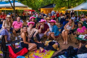 A large group using concert transportation, having a picnic at the concert in pink hats